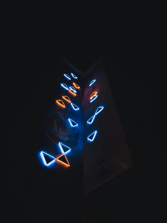 an illuminated sign with a blue arrow and three neon lights in the dark