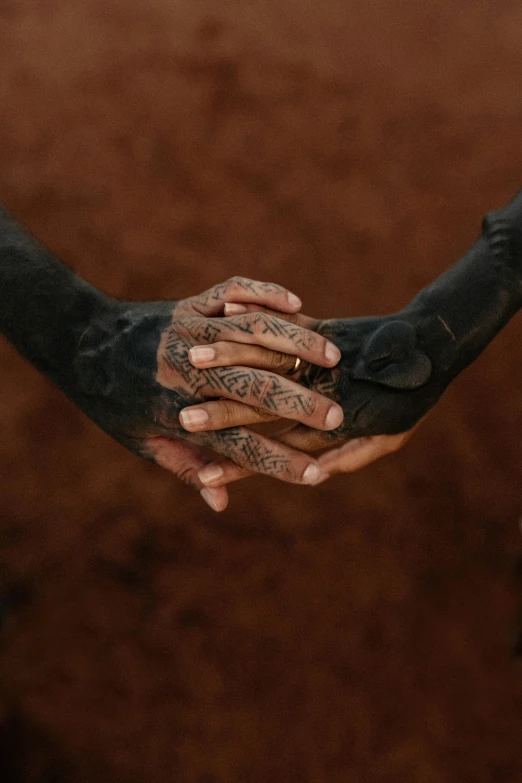 two hands touching each other with tattooed arms