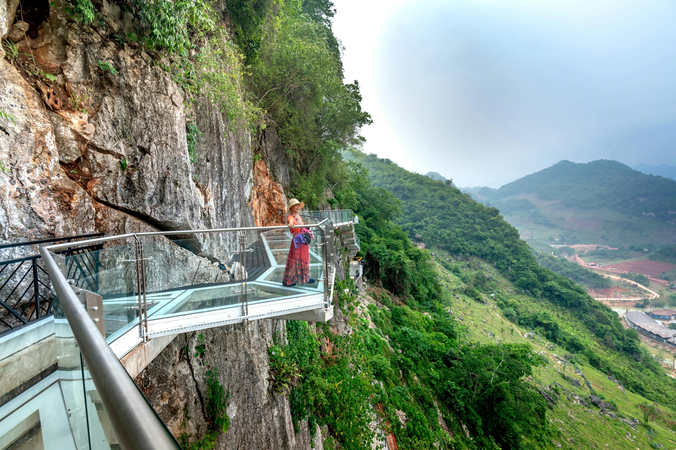 a woman stands at the edge of a railing in front of an overlook