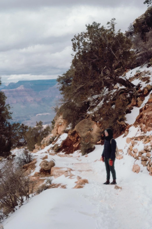 two snowboarders are on a snowy trail that runs along a mountain