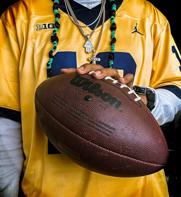 a man holding an football in one hand and a beaded necklace on