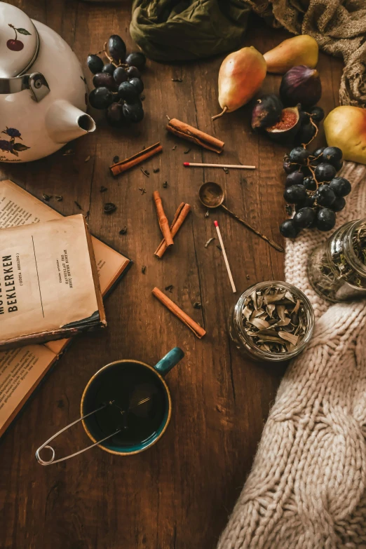 a table with many items that include books, candles, some wine, gs and tea