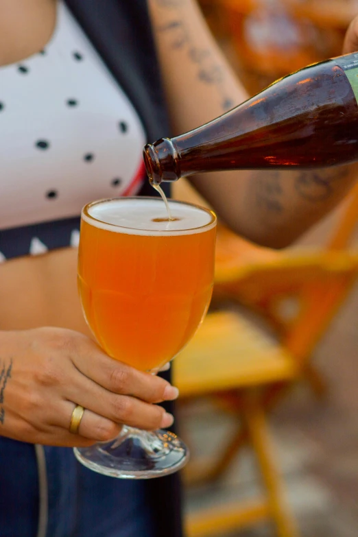 a woman pouring a beer into a wine glass