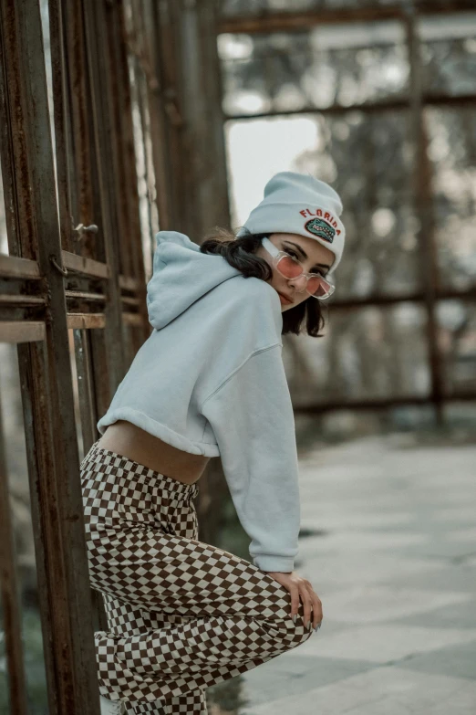 a woman leaning against a wall with a white hoodie on