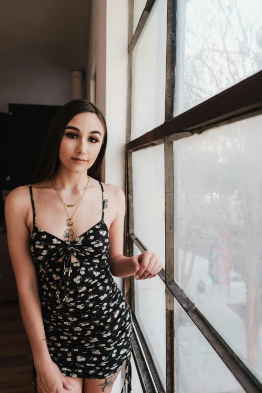 a pretty young lady looking out a window in front of a tree