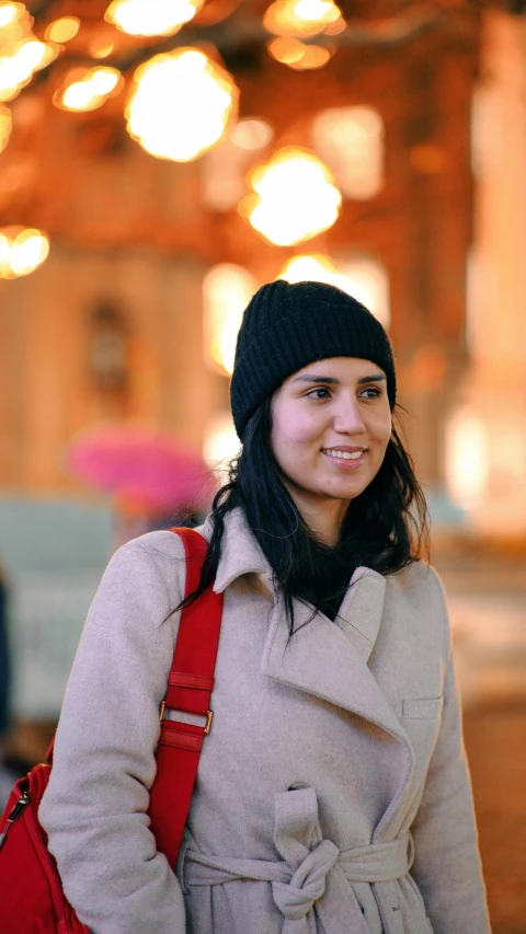 smiling girl wearing a coat, with a red purse and black hat