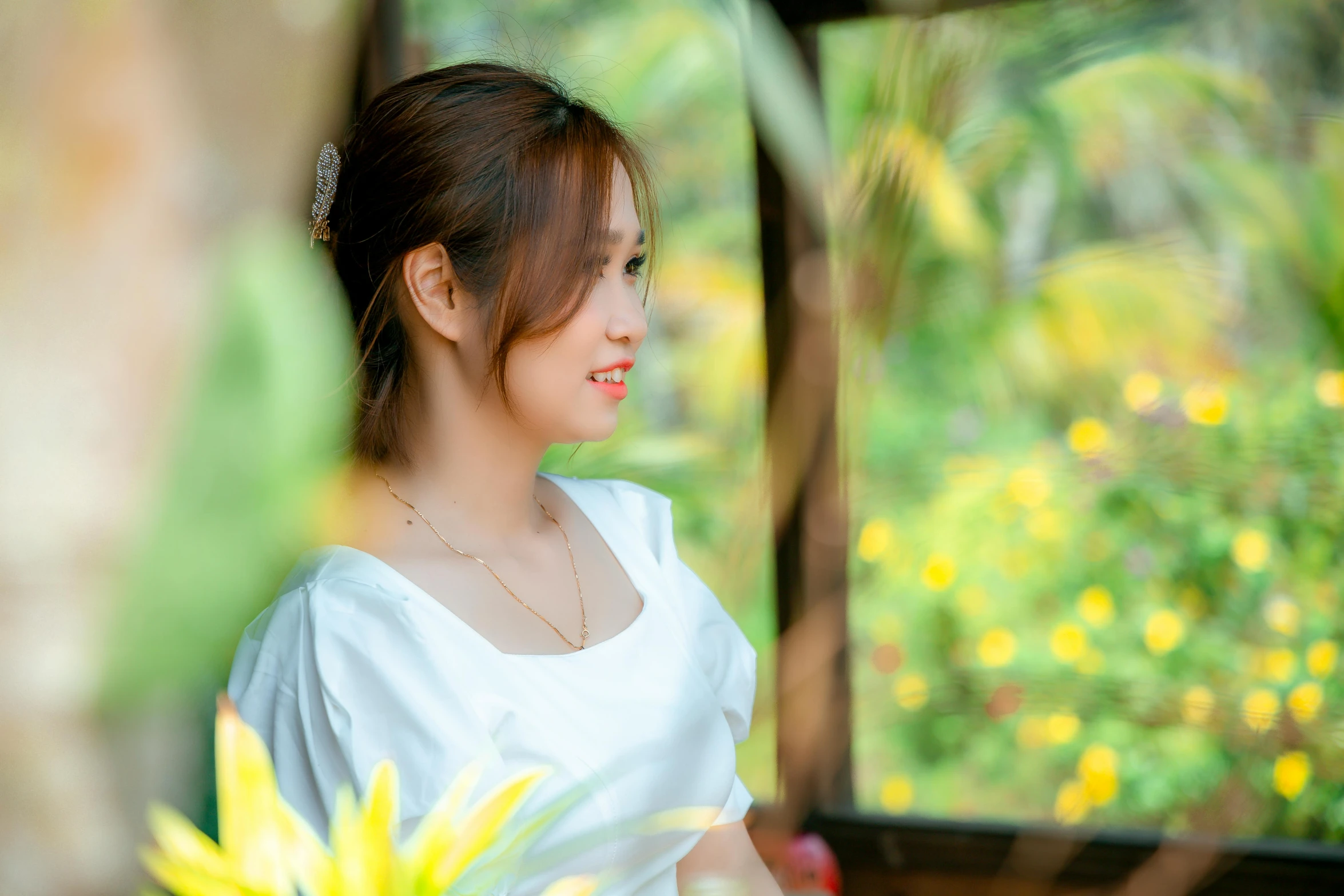 woman in white dress holding onto flowers in front of window