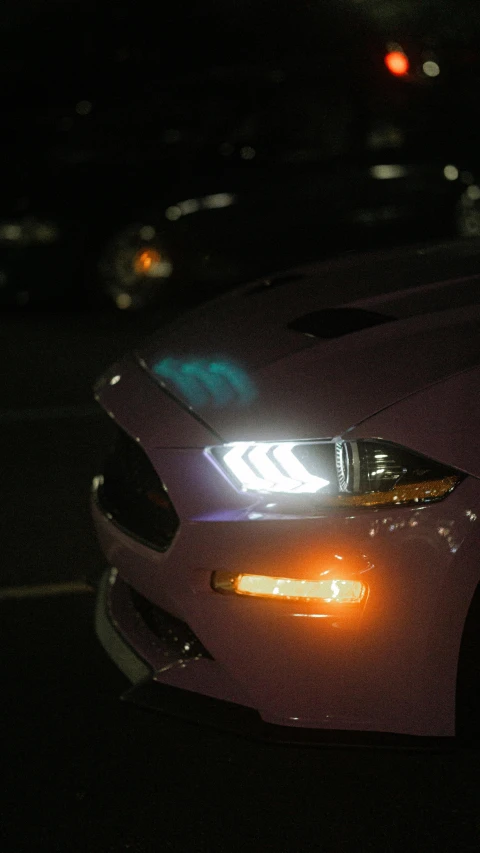 a red car with its lights on at night