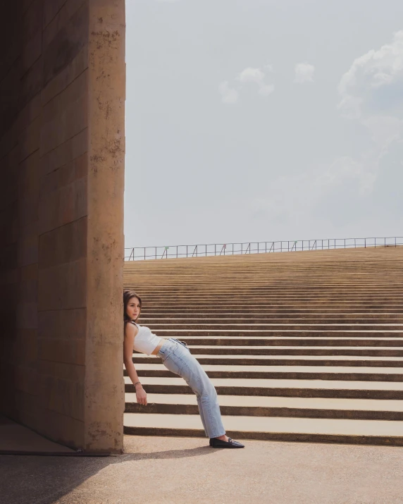 a girl poses in front of the steps at the bottom of a stairway