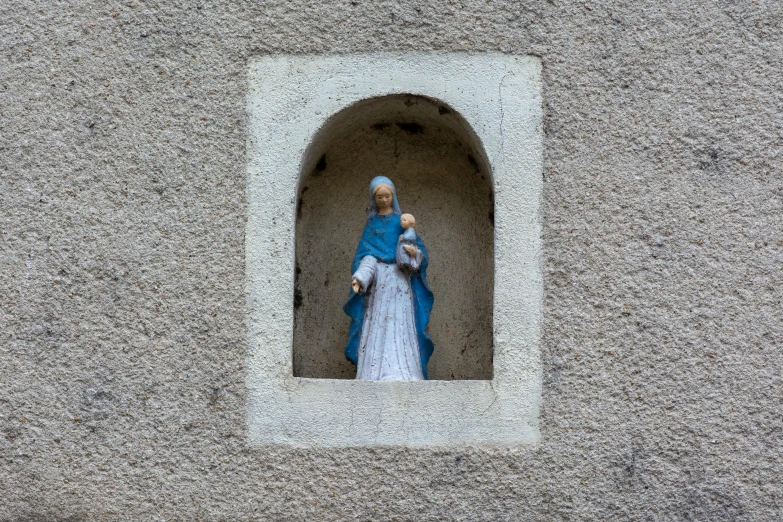 statue with a blue cape and headdress standing inside a small hole