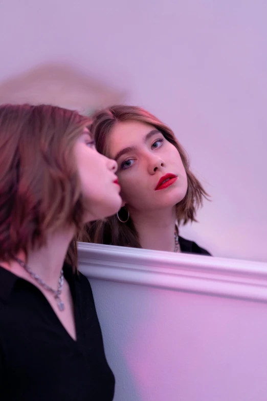 two women in front of a mirror kissing each other