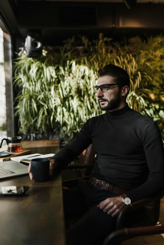 a man sitting at his computer in front of a window