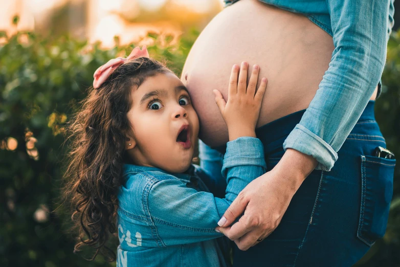 a woman holds her pregnant child's  while it looks at soing