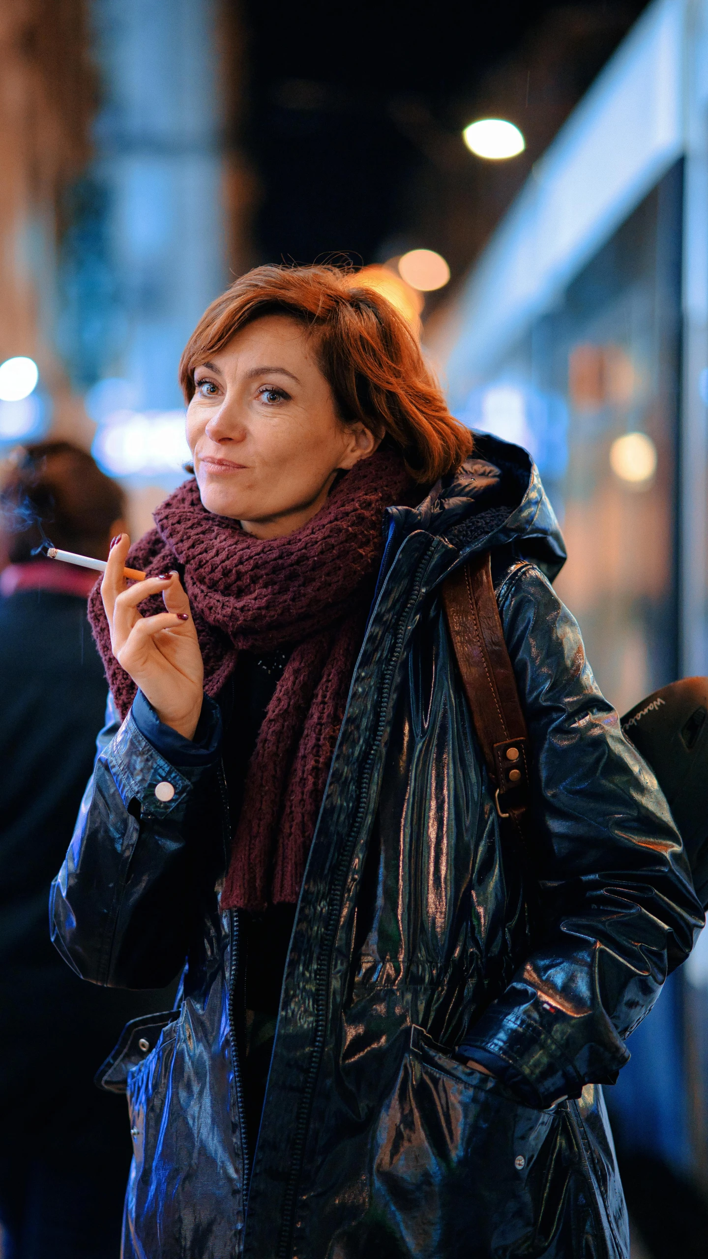 woman smoking a cigarette on the sidewalk in the city