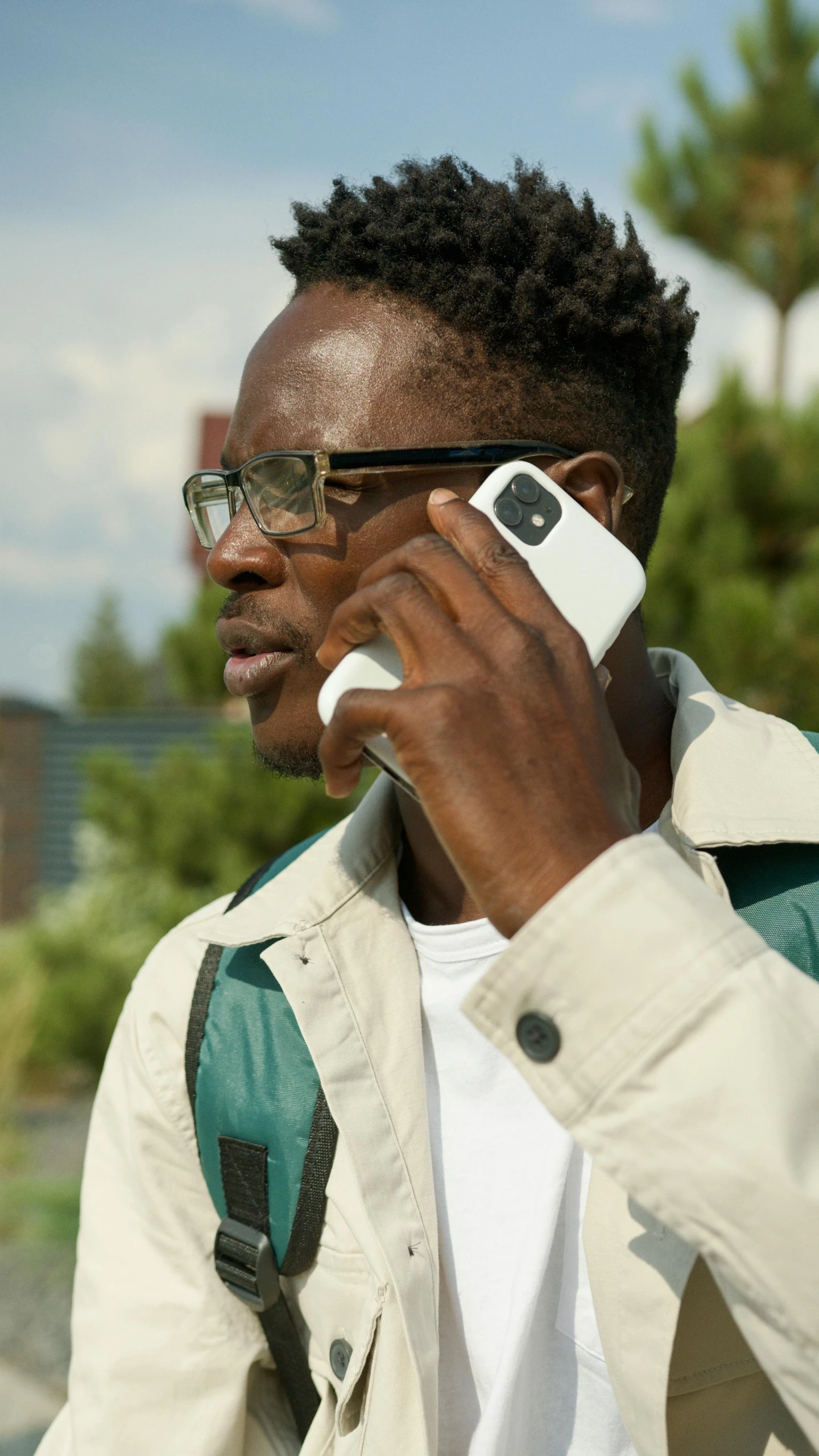 a man wearing glasses using a cell phone while he has earpieces