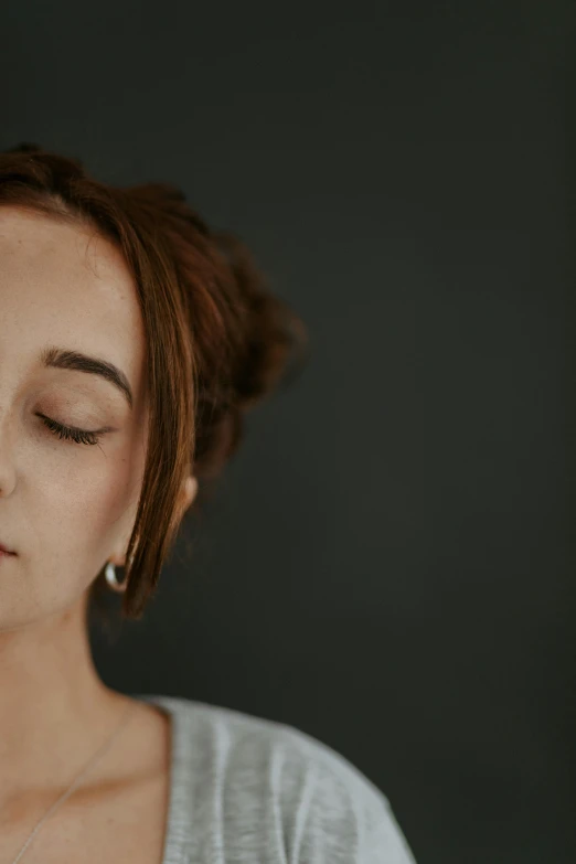 a woman wearing a grey shirt and gold necklace