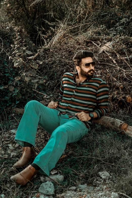 a man in striped shirt sitting on a log