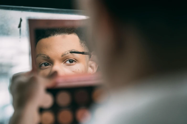 a woman holding an object in front of her face while looking through a mirror