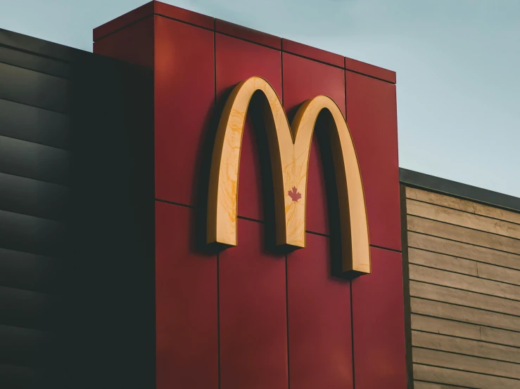 the front of a mcdonald's restaurant with a wooden arch over the entrance