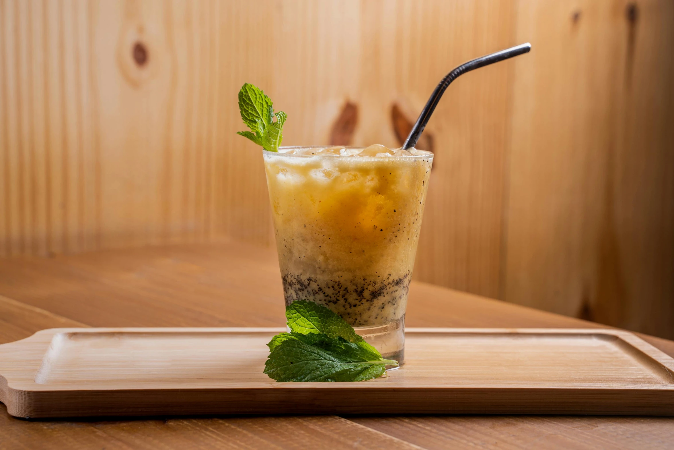 an iced drink with a black straw and mint