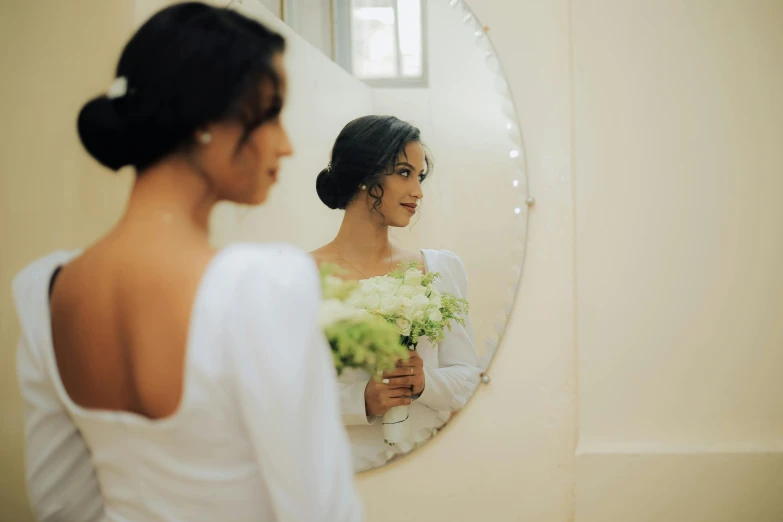 a bride with white flowers is looking in the mirror