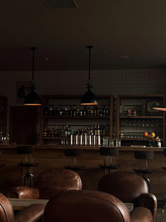 leather chairs in front of bar with open shelves and a glass