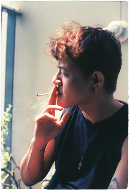 a young person in blue shirt smoking a cigarette