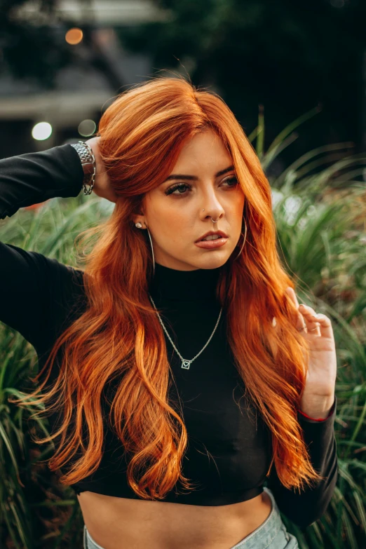 a woman with red hair standing near some plants