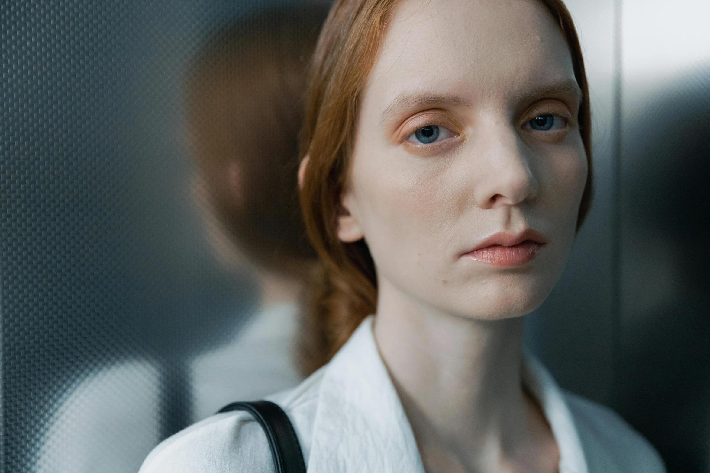 a woman looking at the camera, wearing a white shirt and suspenders