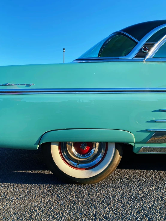 a vintage green car with chrome wheels and fenders