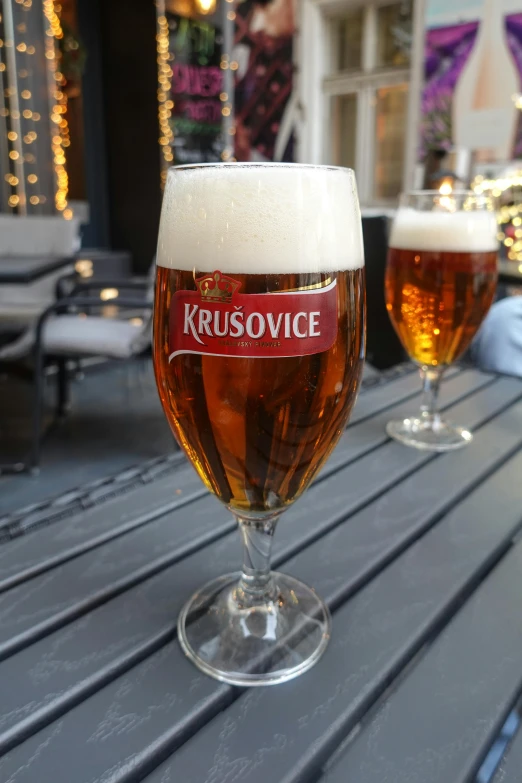 three glasses of beer sitting on a table outside