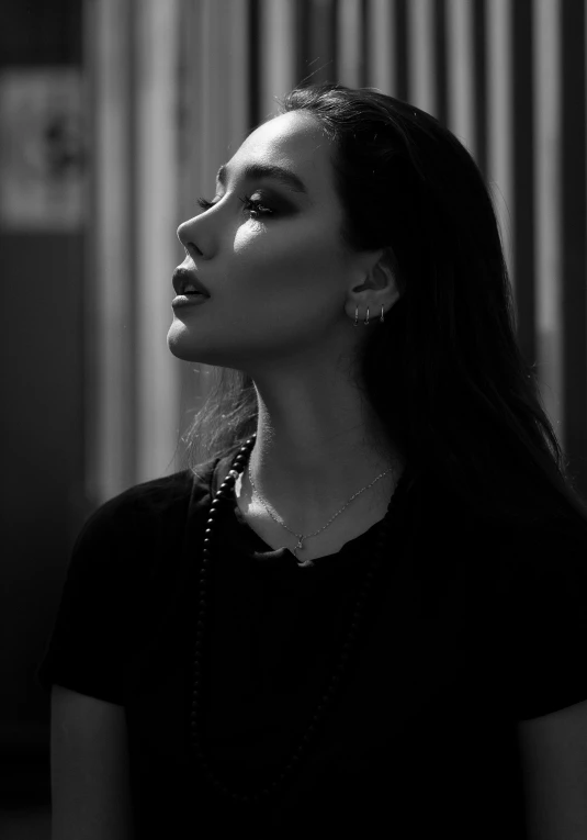 black and white po of woman in dark t - shirt with long hair and silver jewelry