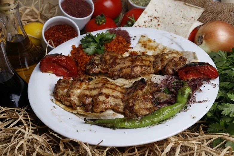 a plate of grilled vegetables and meat on a hay covered floor