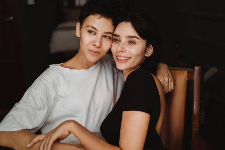 the young woman is hugging her friend on a chair