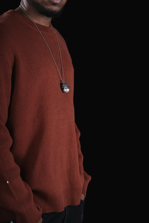 a young black man wearing a sweater and a silver chain