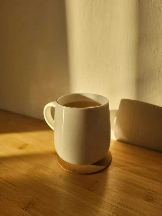 a cup of coffee sits on a table in the sunlight