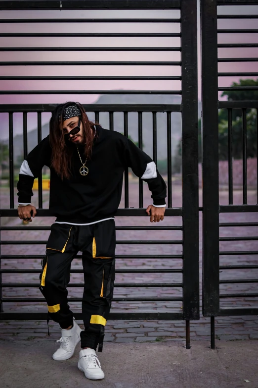 a person with long hair and white shoes stands near some black gates