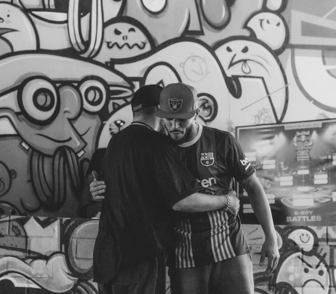 two people that are hugging each other in front of graffiti