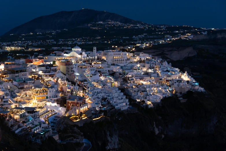 a hill with many white buildings lit up at night