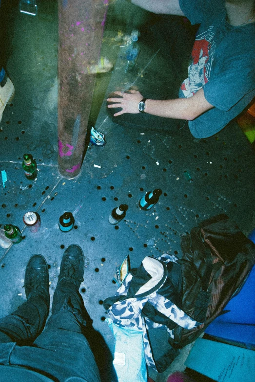 a young person standing on top of a floor next to bottles and debris