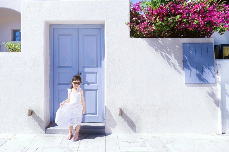 the young woman in white is outside by a blue door