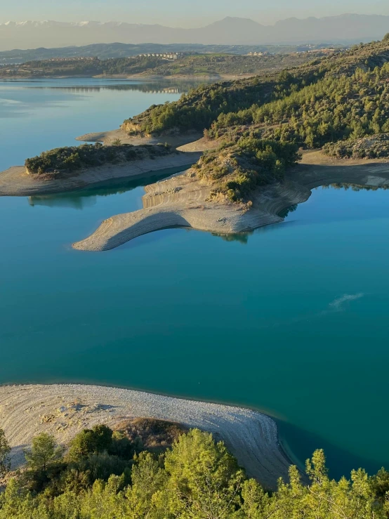 the water has green trees and mountains surrounding it