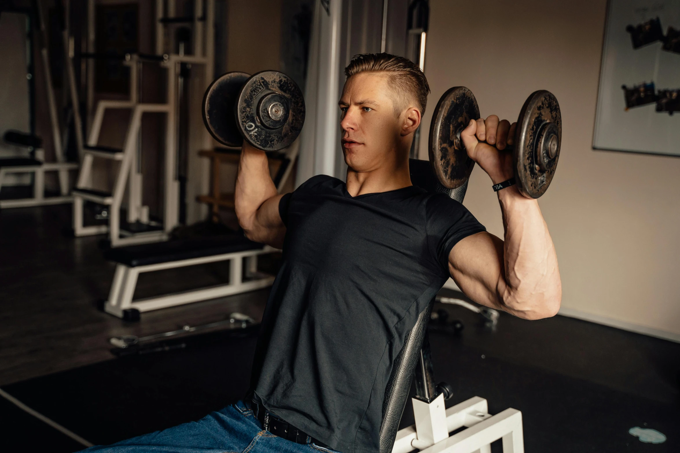 a man holding two olympic weights and sitting in a chair