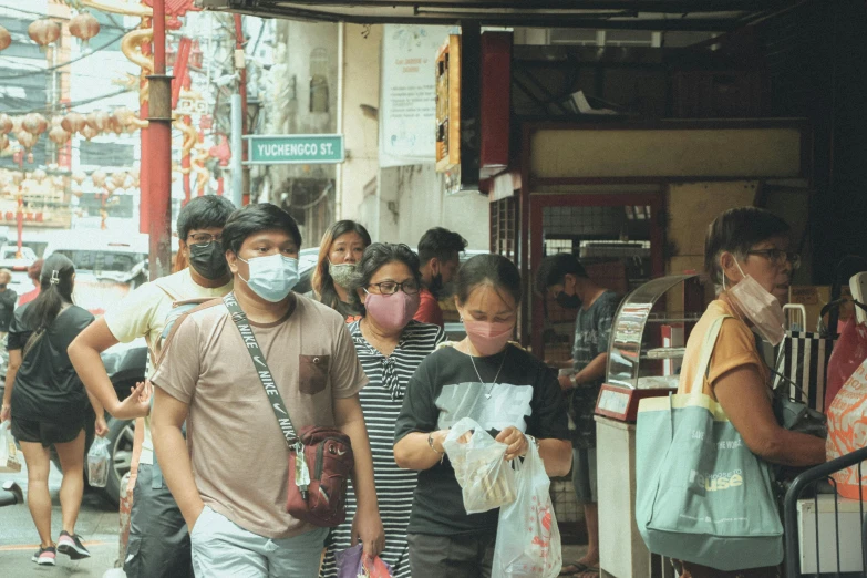 people in masks and wearing masks are walking down the street