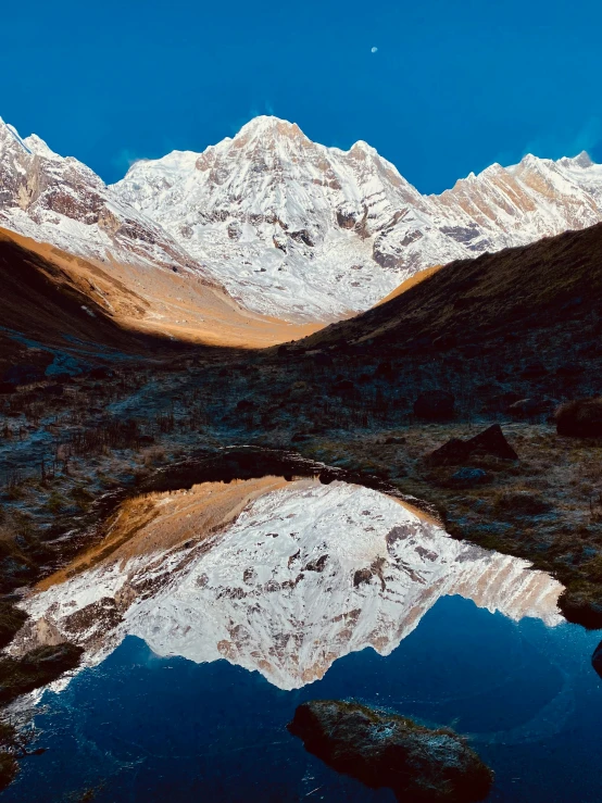 the mountains are reflected in a large pond