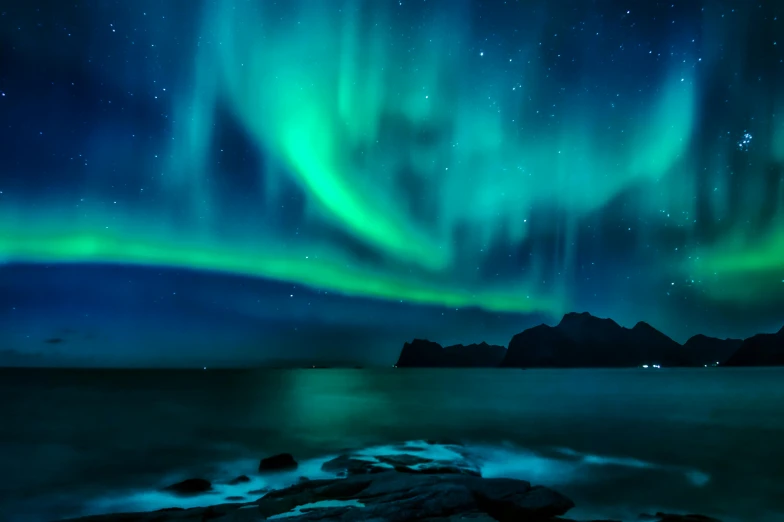 an aurora lights over a body of water near mountains