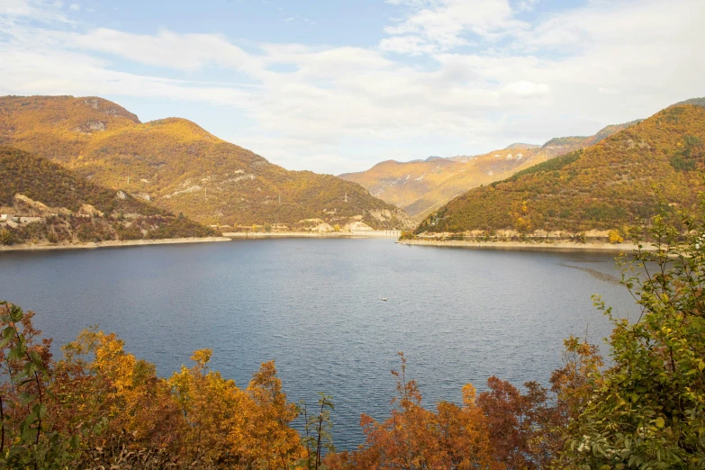 the mountains surrounding a large lake are dotted with foliage