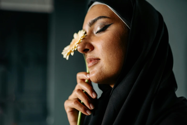 a woman smelling a flower wearing black