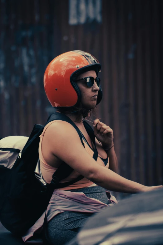 a woman with a red helmet and backpack is sitting on a motorcycle