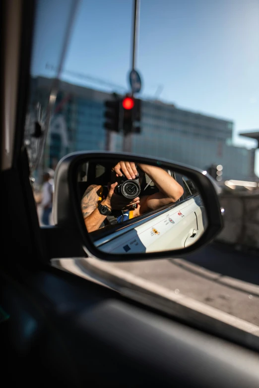 the woman is holding a camera in a side mirror